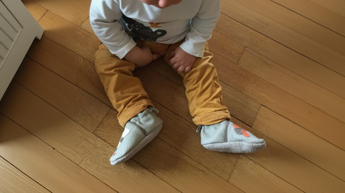 enfant assis sur parquet chaussons souples aux pieds