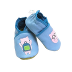 Chaussons bébé en cuir souple bleu motif cochon lunettes et cochon sac à dos, vue croisée mettant en valeur les appliqués et la texture du cuir.