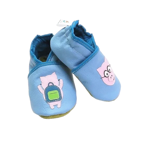 Chaussons bébé en cuir souple bleu motif cochon lunettes et cochon sac à dos, vue croisée mettant en valeur les appliqués et la texture du cuir.