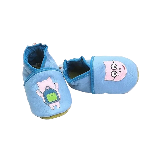Chaussons en cuir souple artisanaux bleu pour bébé avec cochon rose à lunettes sur un pied et cochon avec sac à dos vert sur l’autre, finitions bleu foncé.