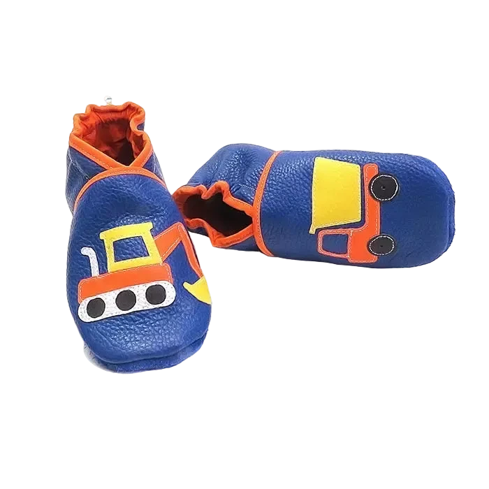 Chaussons en cuir souple artisanaux bleus pour enfant avec pelleteuse et camion benne, vue inclinée avec un chausson allongé.