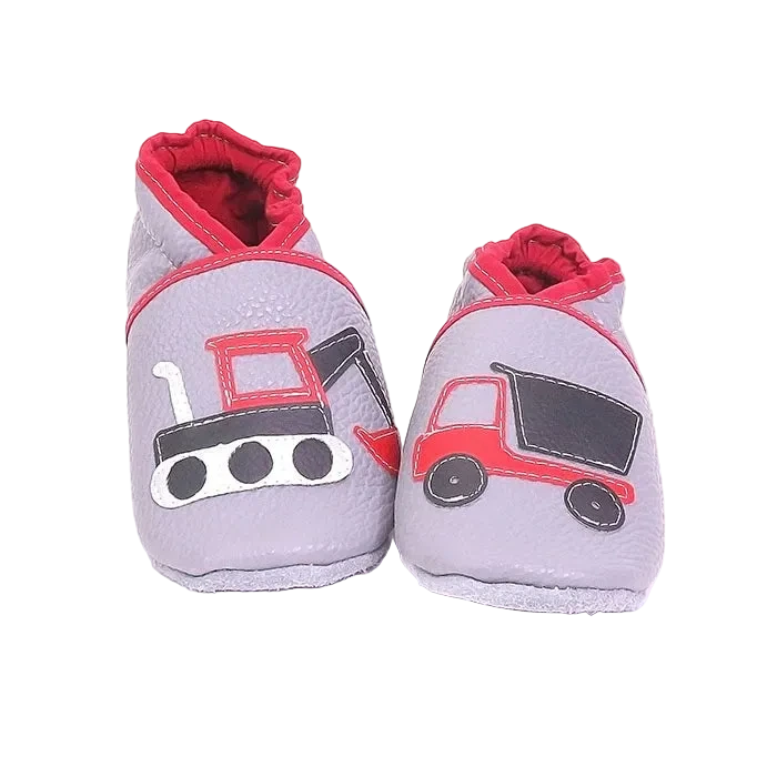 Chaussons en cuir souple artisanaux gris clair pour enfant avec pelleteuse et camion benne rouges, finitions roses.