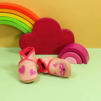 Chaussons en cuir souple artisanaux beige rosé pour bébé avec renard rose sur un pied et cœurs roses sur l’autre.