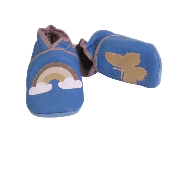 Chaussons bébé en cuir souple bleu avec arc-en-ciel et papillon doré appliqué, fabrication artisanale française.