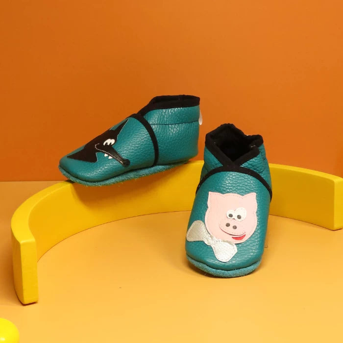Chaussons bébé en cuir souple bleu canard avec motifs loup et cochon.