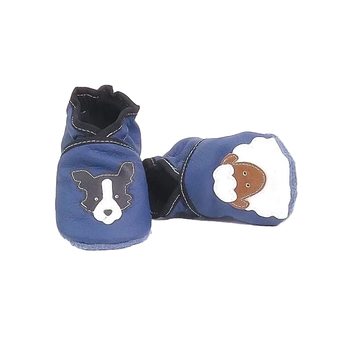 Chaussons bébé en cuir souple bleu avec motifs chien et mouton, vue croisée mettant en valeur la souplesse et les finitions contrastées.