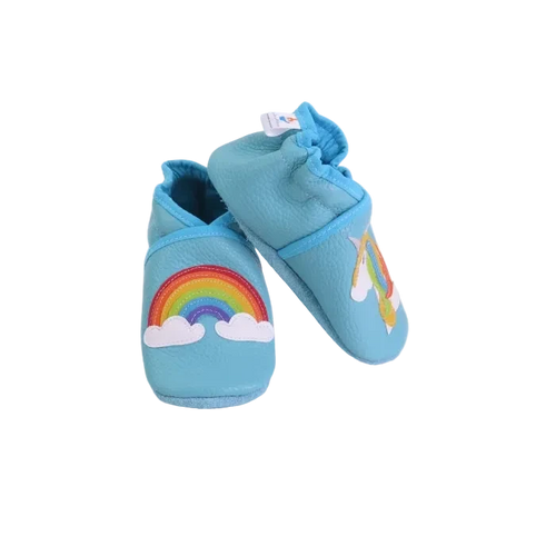 Chaussons bébé bleu ciel avec arc-en-ciel et licorne en cuir souple, vue inclinée.