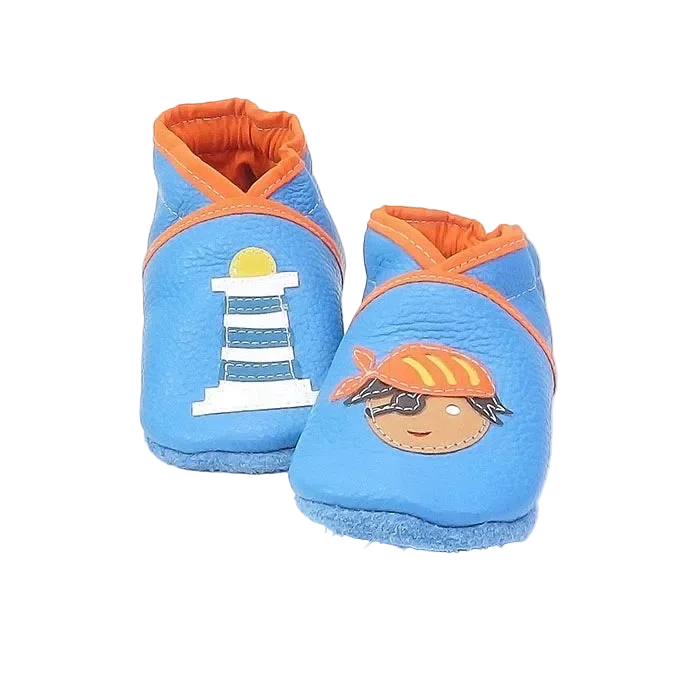 Chaussons en cuir souple artisanaux bleu clair pour bébé avec phare blanc et pirate illustré, détails orange contrastés.