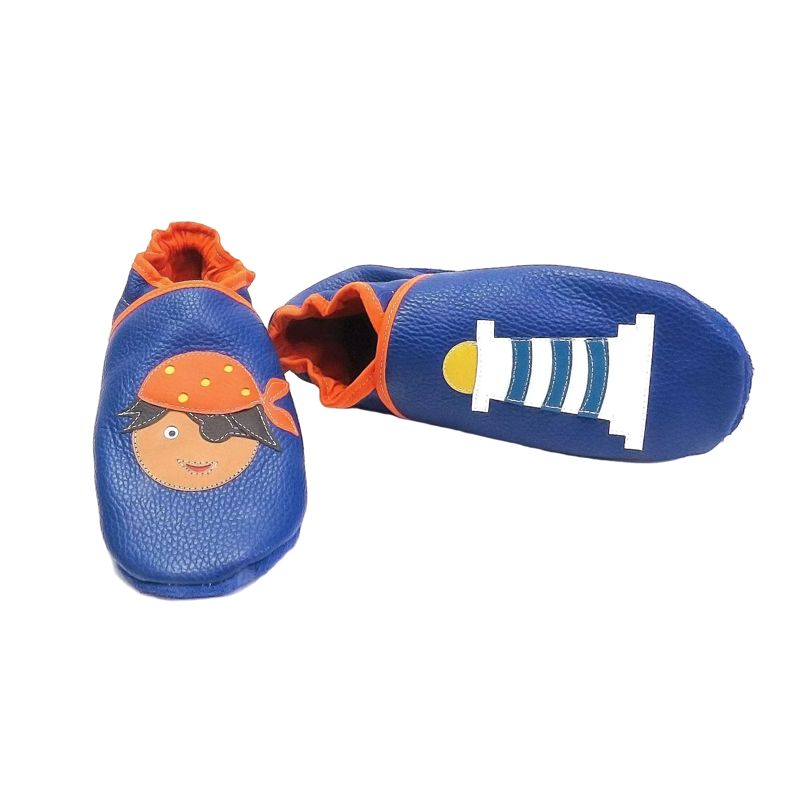 Chaussons en cuir souple artisanaux bleu foncé pour bébé avec pirate sur un pied et phare blanc et bleu sur l’autre, vue avec un chausson allongé.