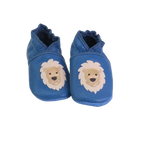 Chaussons bébé en cuir souple bleu avec tête de lion beige appliquée, fabrication artisanale française.