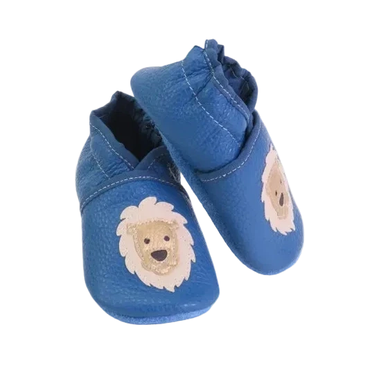 Chaussons bébé en cuir souple bleu avec lion beige cousu main, vue inclinée.
