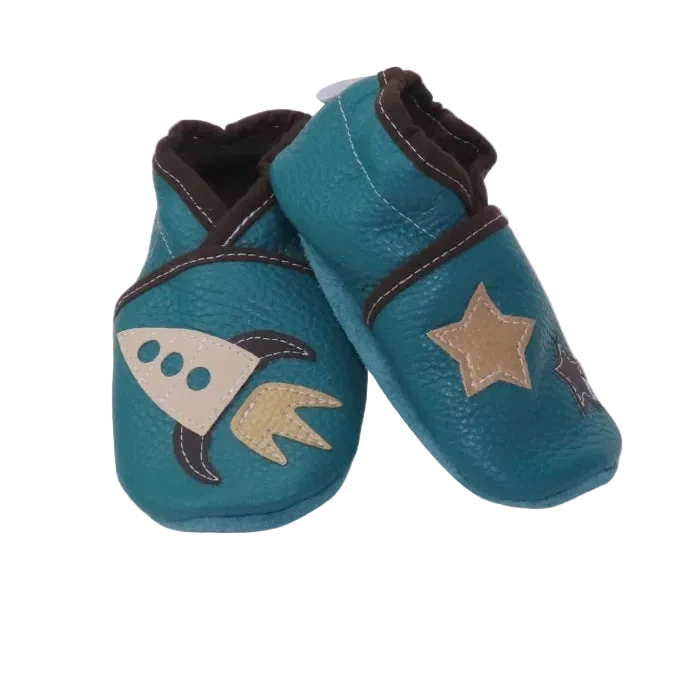 Chaussons bébé en cuir souple bleu pétrole avec fusée beige et étoiles appliquées, fabrication artisanale.