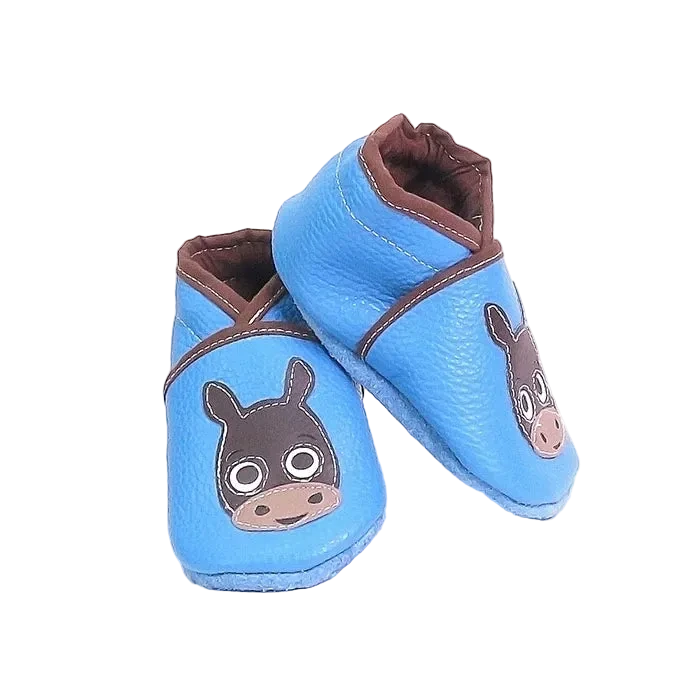 Chaussons en cuir souple artisanaux bleus pour bébé, vue en angle, avec tête de poulain marron et finitions contrastées.