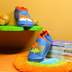 Chaussons bébé en cuir souple bleu avec renard et feuilles d’automne en mise en scène.