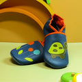 Chaussons bébé en cuir souple bleu avec tortue verte et fleurs colorées appliquées, fabrication artisanale française.