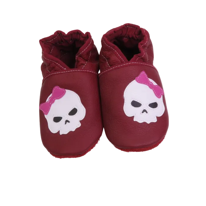 Chaussons bébé bordeaux en cuir souple avec tête de mort et nœud rose.