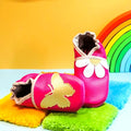 Chaussons bébé en cuir souple fuchsia avec marguerite et papillon doré.