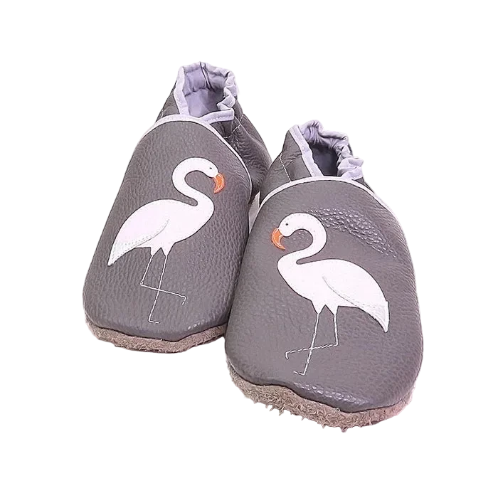 Chaussons bébé en cuir souple gris motif flamant rose, vue de face mettant en valeur les appliqués et la texture du cuir.