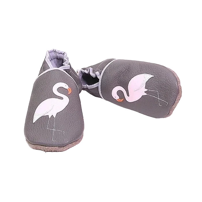 Chaussons en cuir souple artisanaux gris pour bébé avec flamant rose blanc et bec orange illustré sur chaque pied, finitions gris clair.