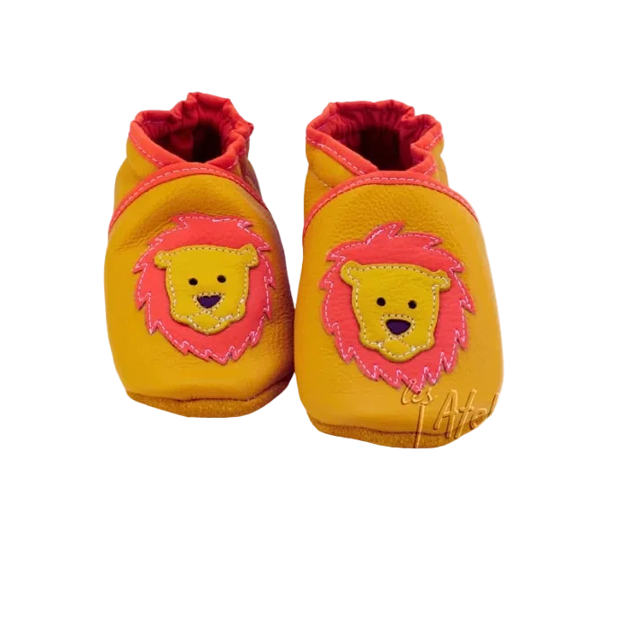 Chaussons bébé en cuir souple jaune avec tête de lion orange et jaune, fabrication artisanale française.
