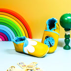 Chaussons en cuir souple jaune pour bébé avec motif fleur marguerite et coccinelle décorative.