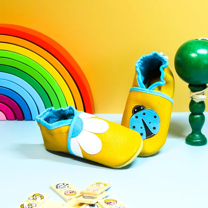 Chaussons en cuir souple jaune pour bébé avec motif fleur marguerite et coccinelle décorative.