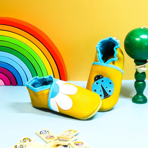 Chaussons en cuir souple jaune pour bébé avec motif fleur marguerite et coccinelle décorative.