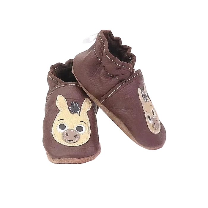 Chaussons bébé en cuir souple marron avec tête d’âne, vue en biais montrant la texture du cuir et la forme enveloppante.