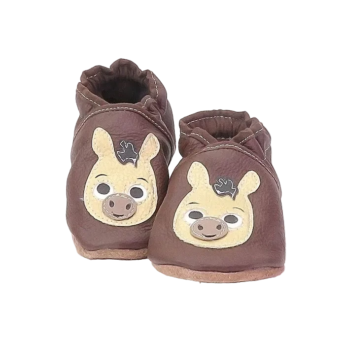 Chaussons en cuir souple artisanaux marron pour bébé avec tête d’âne beige appliquée sur chaque pied.