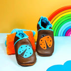 Chaussons bébé en cuir souple marron avec motif coccinelle orange et bleue appliqué sur le dessus.