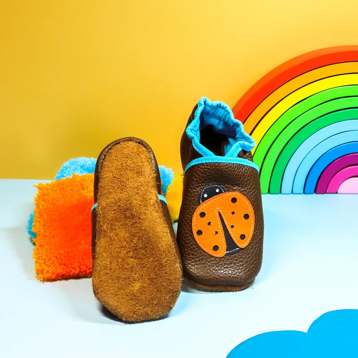 Chaussons en cuir souple marron pour bébé avec coccinelle décorative et semelle en cuir retourné antidérapante.