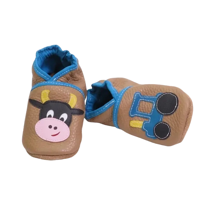 Chaussons bébé marron vache et tracteur en cuir souple, vue inclinée.