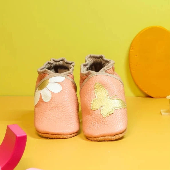 Chaussons bébé pêche en cuir souple avec marguerite et papillon doré.