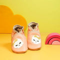 Chaussons bébé en cuir souple pêche avec tête de mort et nœud doré.