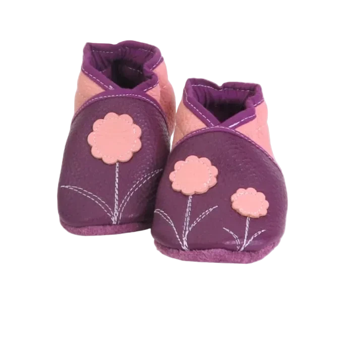 Chaussons bébé en cuir souple prune et rose poudré avec fleurs décoratives cousues, vue de face.