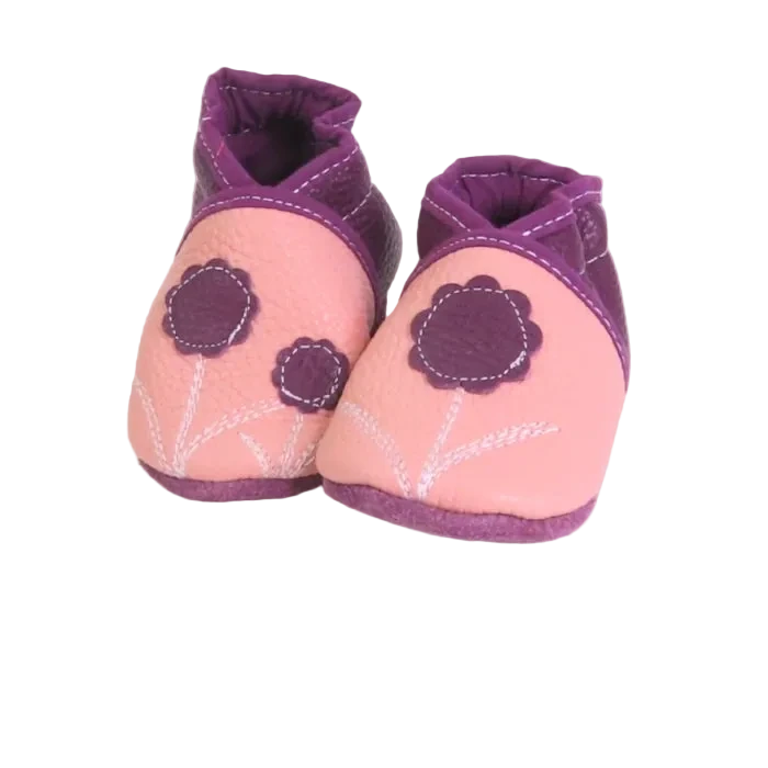 Chaussons bébé en cuir souple rose poudré et prune avec fleurs décoratives, vue inclinée.