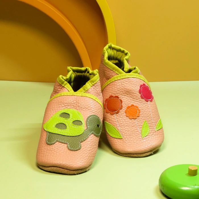 Chaussons en cuir souple pour bébé rose avec tortue verte et fleurs colorées, finitions vert anis.