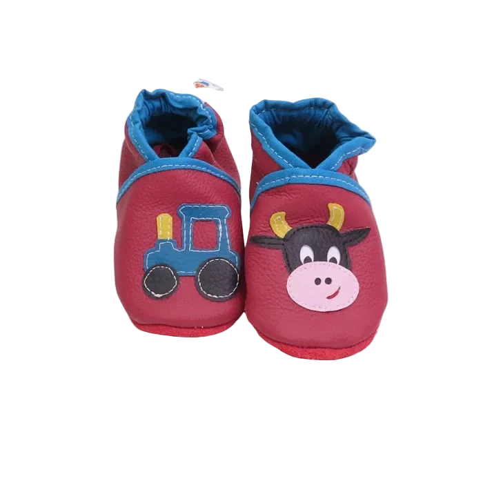 Chaussons bébé en cuir souple rouge framboise avec vache et tracteur appliqués.