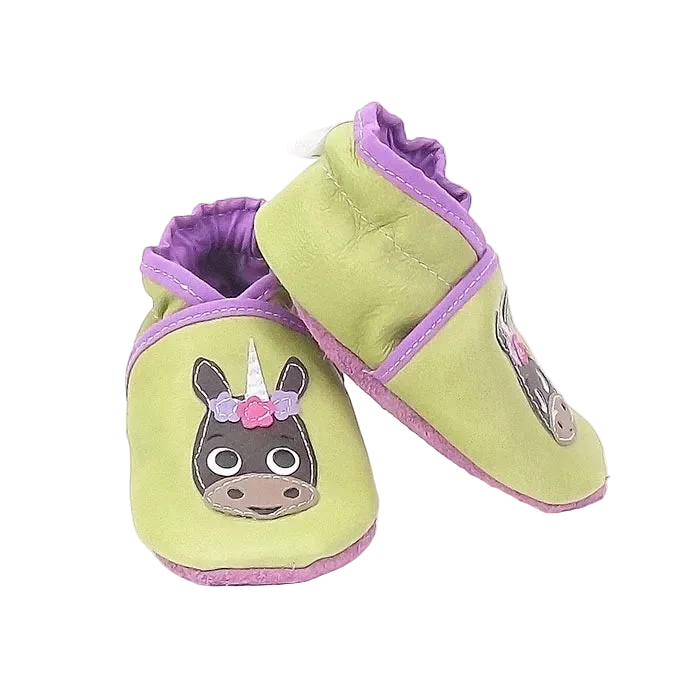 Chaussons bébé en cuir souple vert anis avec licorne fleurie, vue en biais montrant la texture du cuir et la souplesse du modèle.
