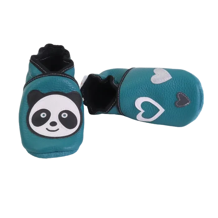 Chaussons en cuir souple vert canard pour bébé avec tête de panda sur un pied et cœurs sur l’autre.