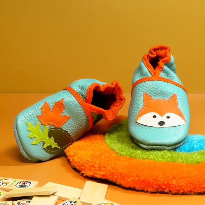 Chaussons bébé en cuir souple vert d’eau avec motif renard et feuilles d’automne.