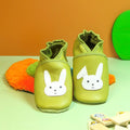 Chaussons bébé en cuir souple vert anis avec motif lapin blanc, fabrication artisanale et cuir texturé.