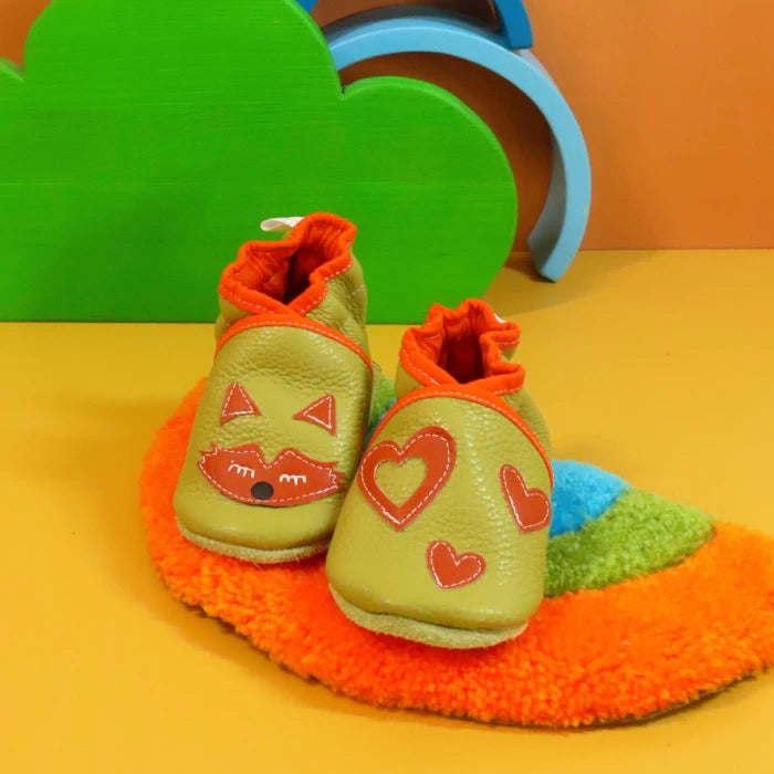 Chaussons en cuir souple artisanaux vert olive pour bébé avec cœurs bleus, vue montrant la semelle en cuir.