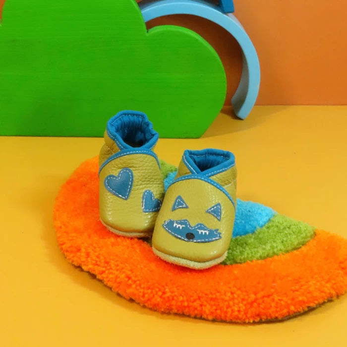 Chaussons en cuir souple artisanaux vert olive pour bébé avec renard bleu et cœurs bleus, finitions assorties.