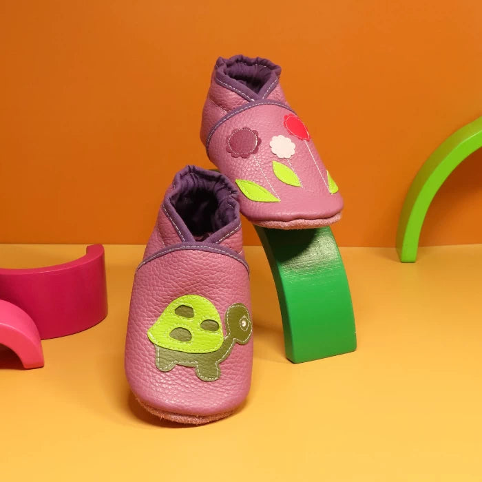 Chaussons en cuir souple pour bébé vieux rose avec motif tortue et fleurs décoratives, fabrication artisanale française.