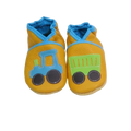 Chaussons en cuir souple artisanaux jaunes pour enfant avec tracteur bleu sur un pied et remorque verte sur l’autre, finitions bleues.