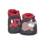 Chaussons en cuir souple artisanaux noirs pour enfant avec tracteur rouge sur un pied et petit taureau marron sur l’autre, finition élastiquée rouge.