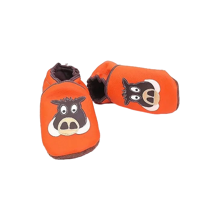 Chaussons en cuir souple artisanaux orange pour enfant, vue en angle, avec tête de sanglier marron et beige.