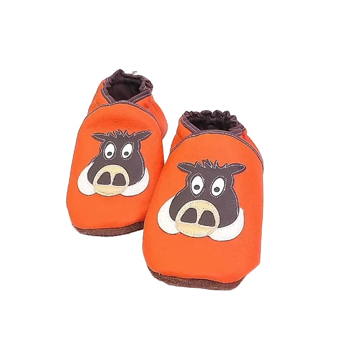 Chaussons en cuir souple artisanaux orange pour enfant avec tête de sanglier marron et beige, finitions marron foncé.