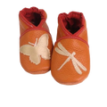 Chaussons en cuir souple artisanaux orange pour enfant, avec papillon crème sur un pied et libellule crème sur l’autre, finition élastiquée .